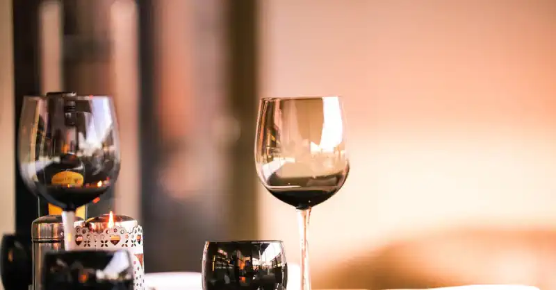 Eleganter gedeckter Tisch mit Weingläsern und brennender Kerze, stimmungsvolles Abendambiente